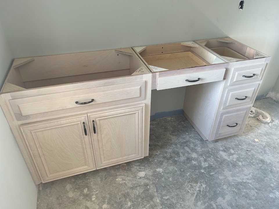 White kitchen counter with shaker-style drawers, black metal handles, and adjacent light grey flooring