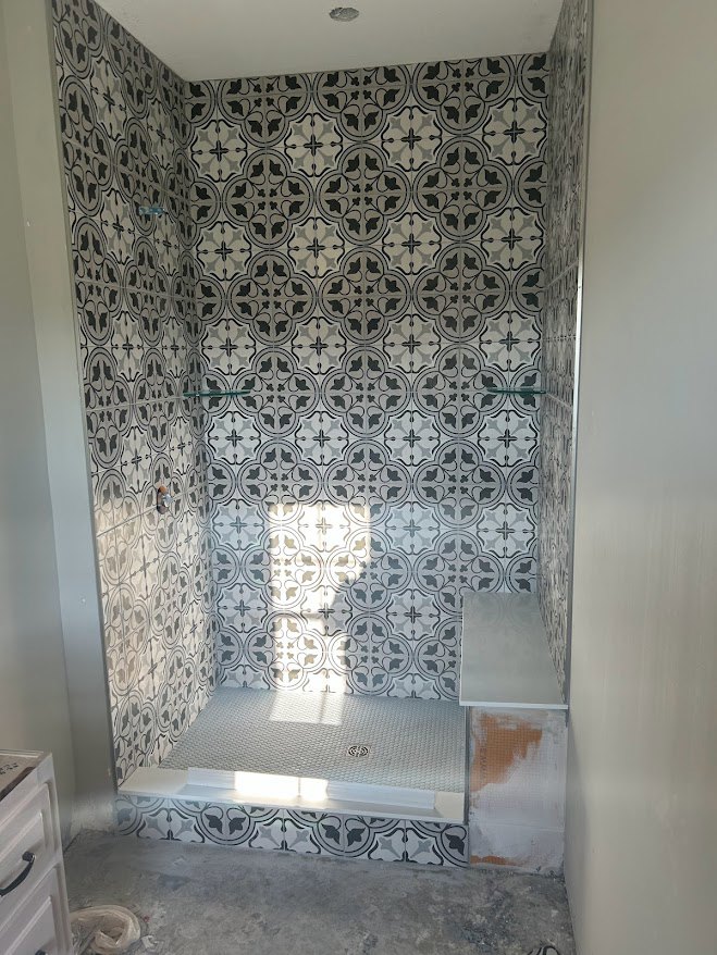 Walk-in shower with large-format tile walls, matching tile floor, and glass enclosure in a modern bathroom