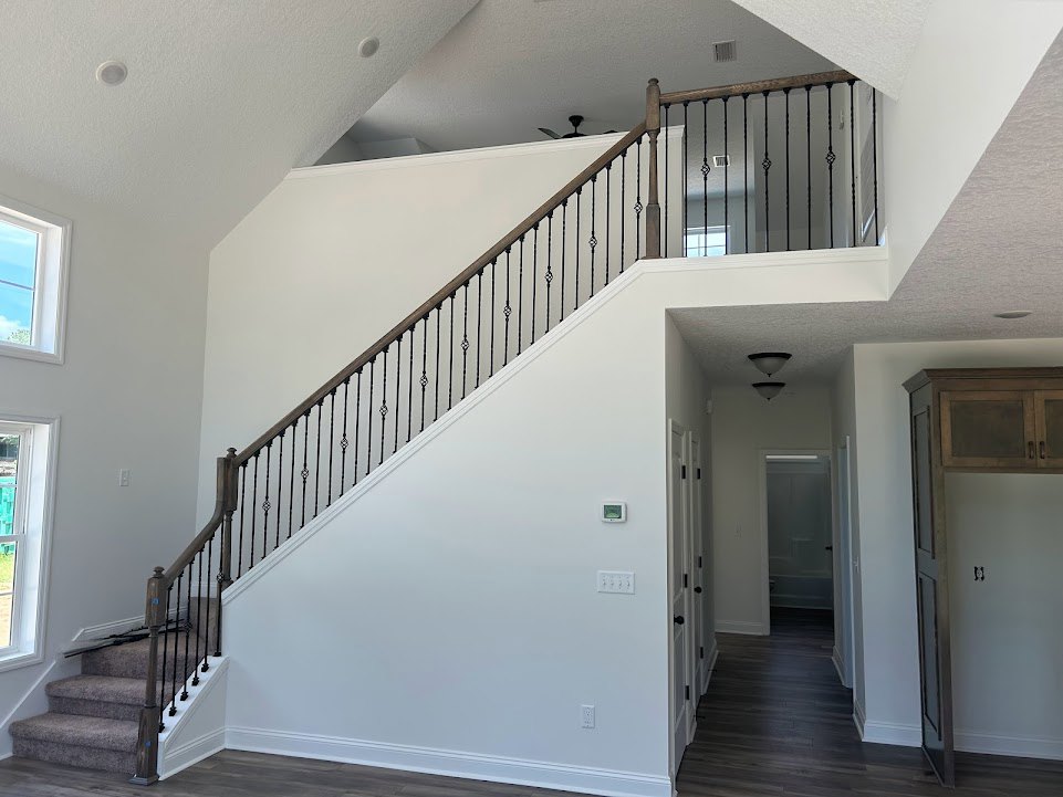 Modern staircase with black metal railings, white plaster walls, blue window frame, and white door with black trim