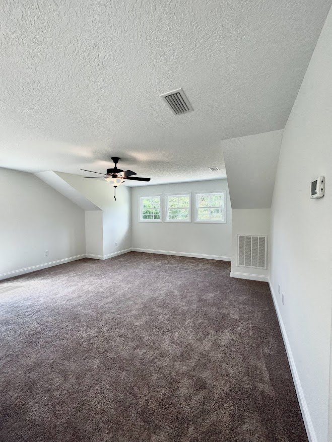 Carpeted room with white-trimmed windows, ceiling fan with light, and ceiling vent