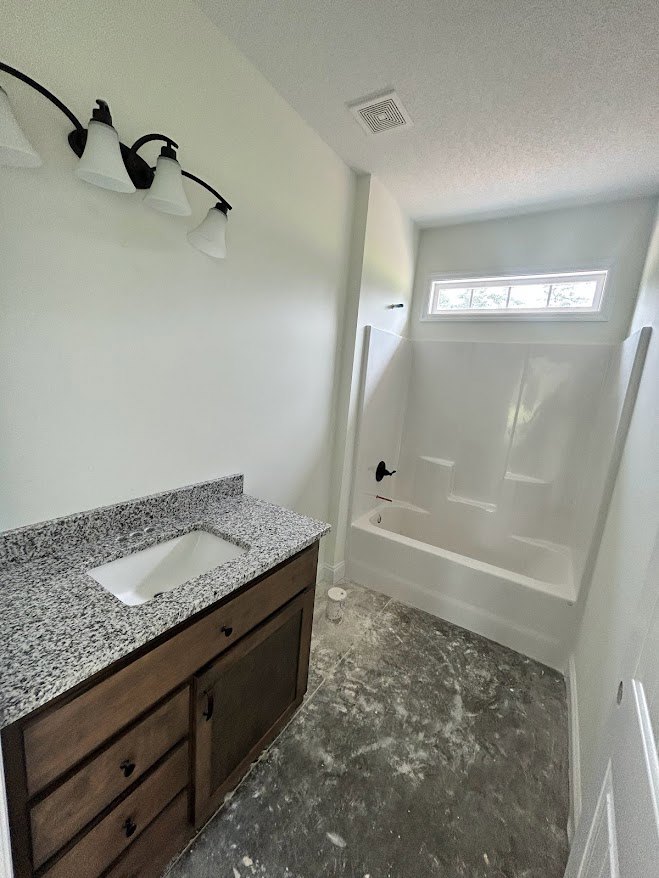 Modern bathroom featuring a freestanding bathtub, white ceramic sink with chrome faucet, light gray tile walls, wood cabinetry, and sleek drawers