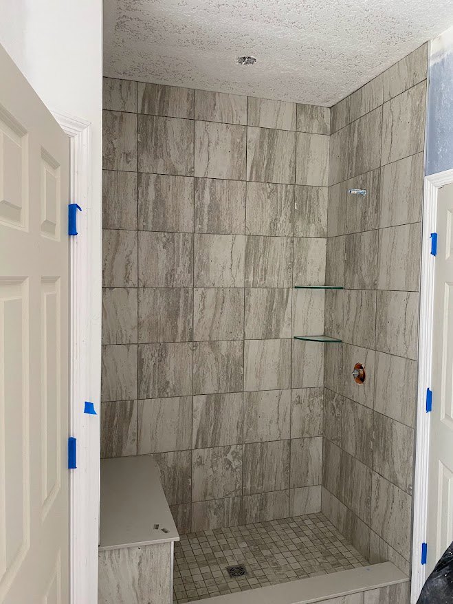 Shower with light-colored tile walls, built-in shelves, and marble tile floor in a modern bathroom