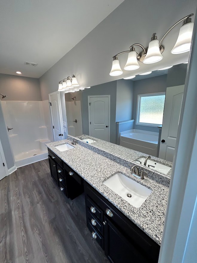 Marble countertop with white sink and chrome faucet, freestanding bathtub, frosted glass window, white door with black knobs, row of ceiling lights, light tile flooring