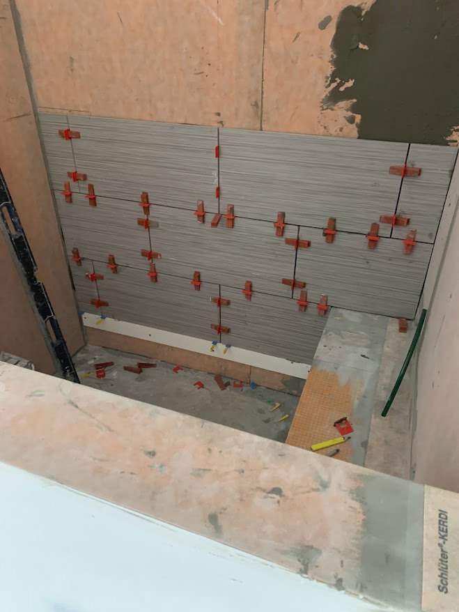 Tile wall with red pegs and green pipe, close-up view of construction materials and finishes