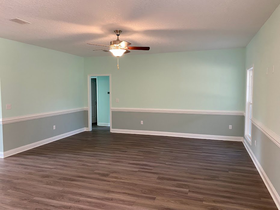 Hardwood floor room with white walls and trim, ceiling fan with light, blue door featuring black handle