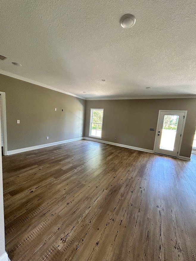 Room with light hardwood flooring, white plaster walls, white framed window, and white door with glass insert.