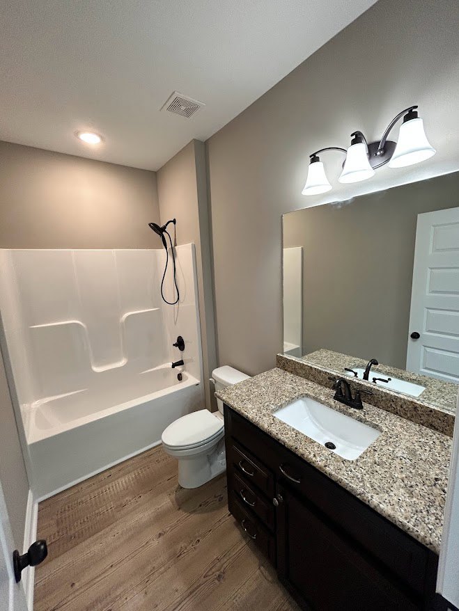 Marble countertop with white sink, chrome faucet, and adjacent toilet in tiled bathroom with neutral walls