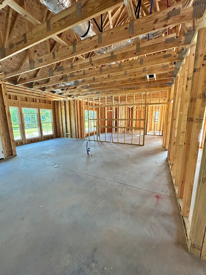 Exposed wood ceiling beams, concrete floor, row of large windows, unfinished walls, visible ductwork