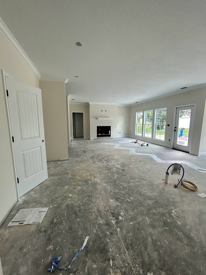 Living room with plaster walls, two fireplaces, blue painter’s tape on hardwood floor, newspaper on wooden table, glass-paneled door, white door with black handle, exposed pipe