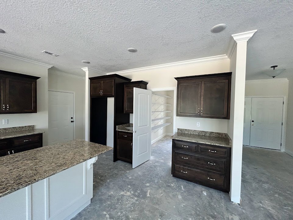 Granite countertops with wood cabinetry, stainless steel appliances, and a white door with silver handle in a modern kitchen