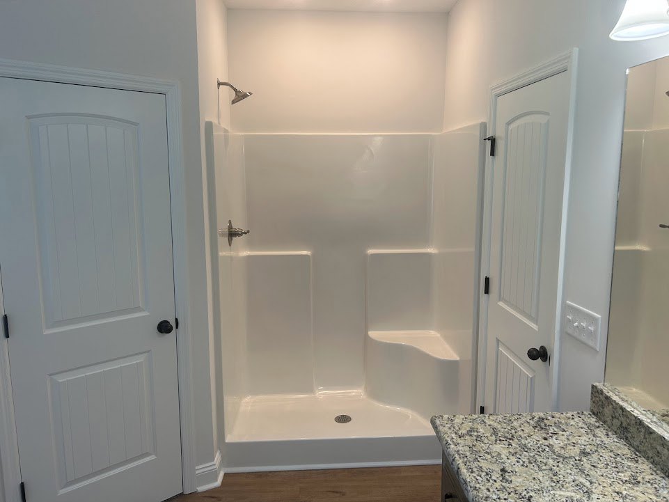 Bathroom featuring a glass-enclosed white shower, marble countertop vanity with white cabinetry, black hardware on doors and drawers, and recessed lighting overhead