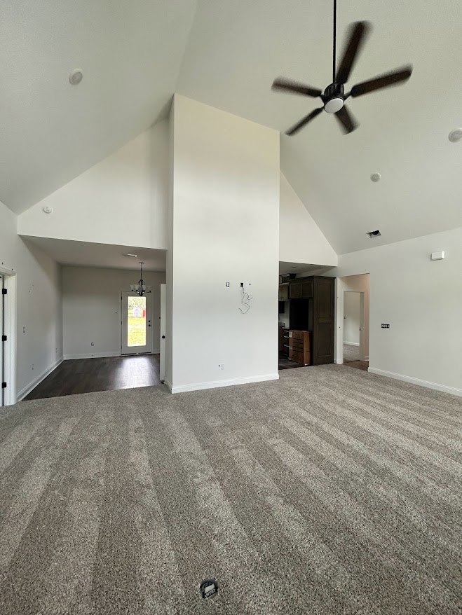 Carpeted room with white ceiling fan and light, neutral walls, and plaster ceiling