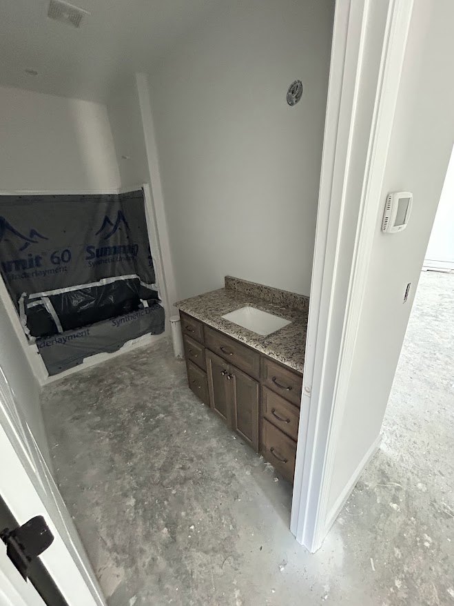 Bathroom with white countertop and built-in sink, light wood cabinetry, rectangular window above, tiled walls, and a bench along one side.