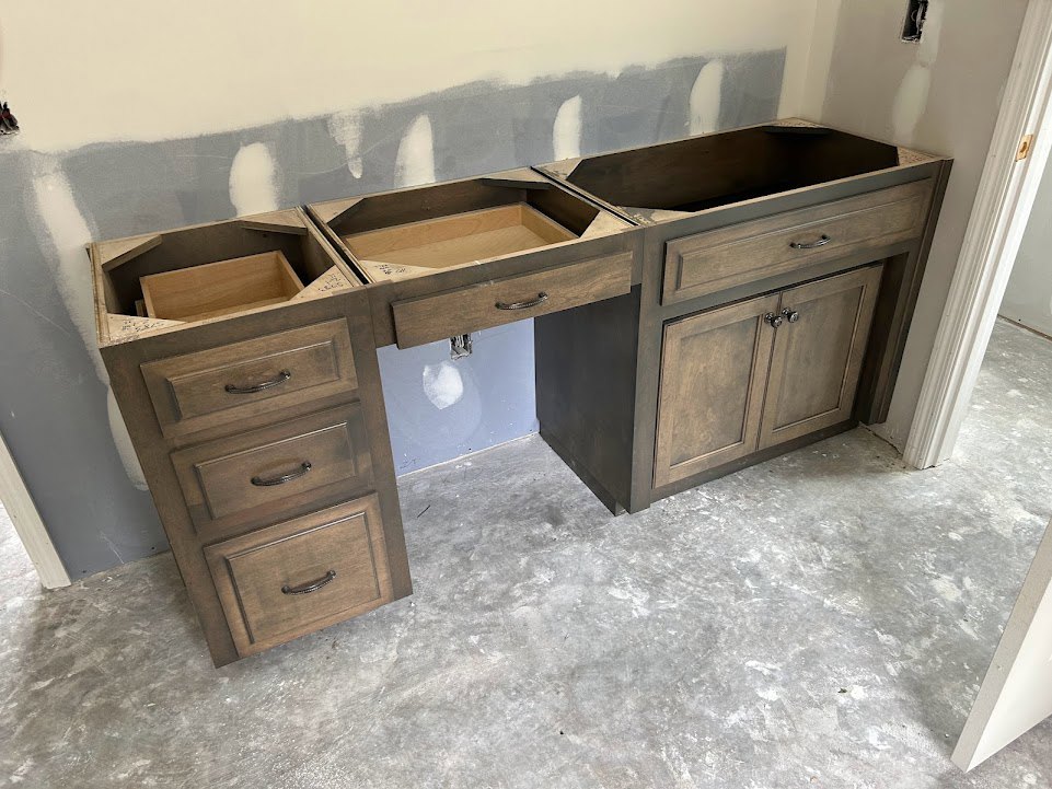 Light grey countertop with white drawers and cabinets, stainless steel sink, concrete floor, and smooth grey backsplash in a modern kitchen.