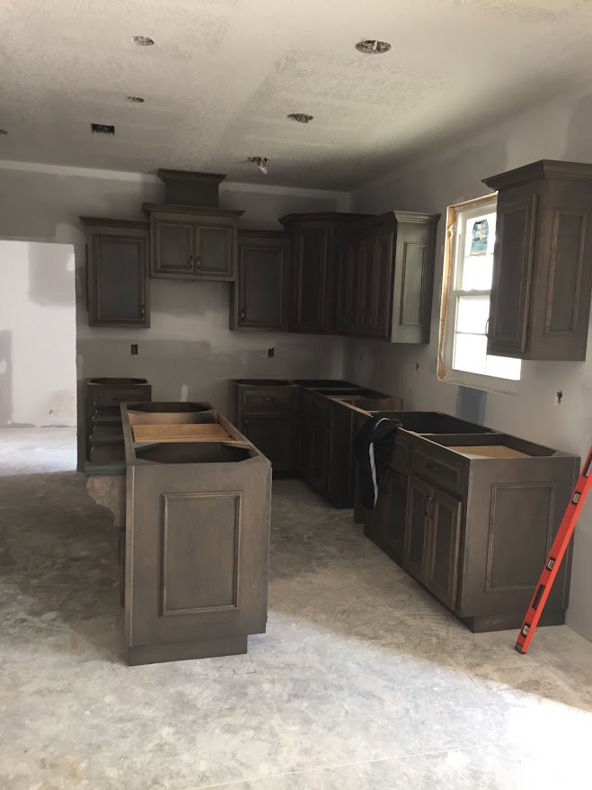 Kitchen with dark wood cabinets, built-in ladder on rails, light countertops, stainless steel sink, and large window letting in natural light