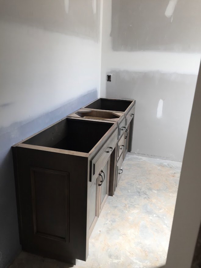 Bathroom vanity with marbled countertop, undermount sink, and light wood cabinetry against a tiled wall