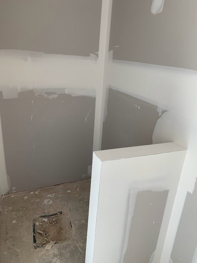 White-walled room with white trim featuring a hole in the wall and debris on the floor