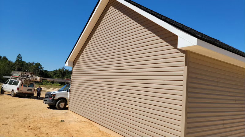 White pickup truck parked on gravel driveway in front of modern house with light-colored siding and large windows