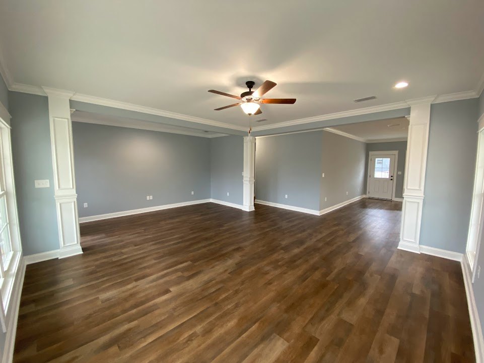 Ceiling fan with light fixture above hardwood floors, white door with window and light switch, plaster walls and ceiling