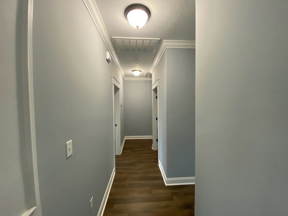 Hallway with dark wood floors, white walls featuring black trim, white railing, and a modern ceiling light fixture