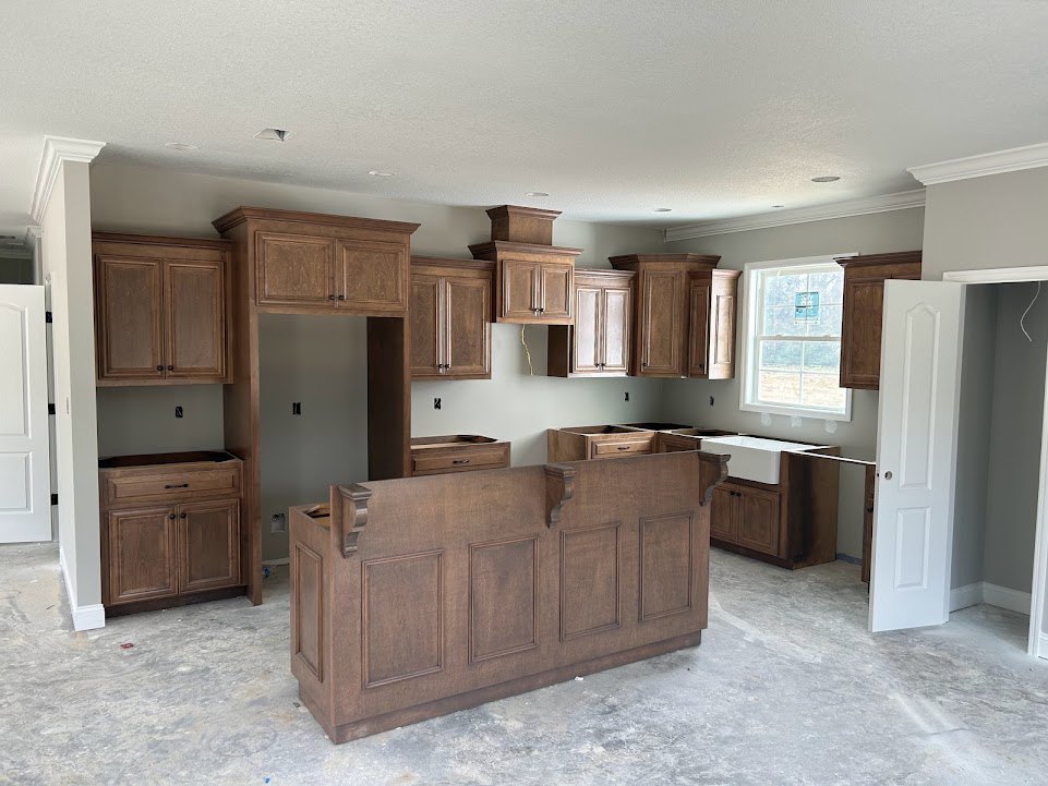 Kitchen featuring wood cabinets, white door, light-colored flooring, and built-in drawers with modern hardware