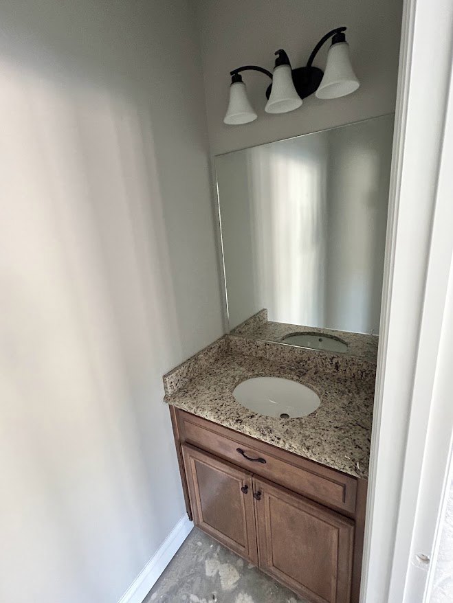 Modern bathroom featuring a white ceramic sink with chrome faucet, rectangular mirror above, light gray tile backsplash, wood vanity with drawers, and neutral painted walls