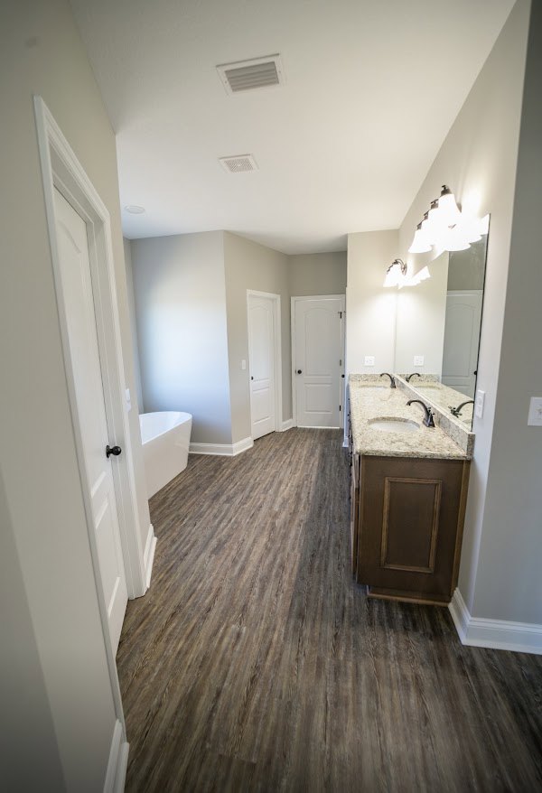 Bathroom with wood flooring, white plaster walls, rectangular window, and modern sink with chrome faucet
