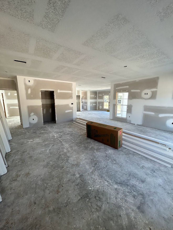 White-walled room with marble flooring, brown cardboard box on the floor, door with glass window, plaster ceiling