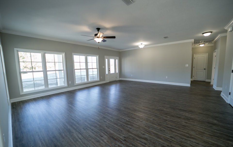 Room with wood flooring, white walls, ceiling fan with light, multi-pane windows, and a white door with black knobs and glass panels