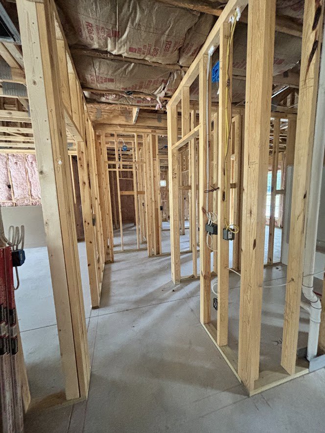 Wood-framed interior with exposed beams, concrete floor, and large white construction bag with red text