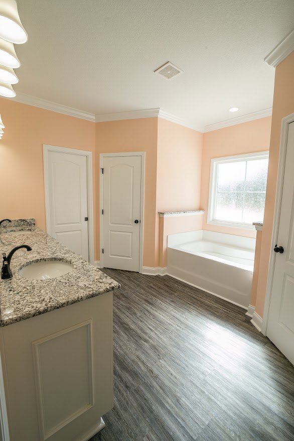 Bathroom featuring marble countertops, freestanding bathtub, light fixture, white cabinetry, tiled floor, and neutral wall finishes