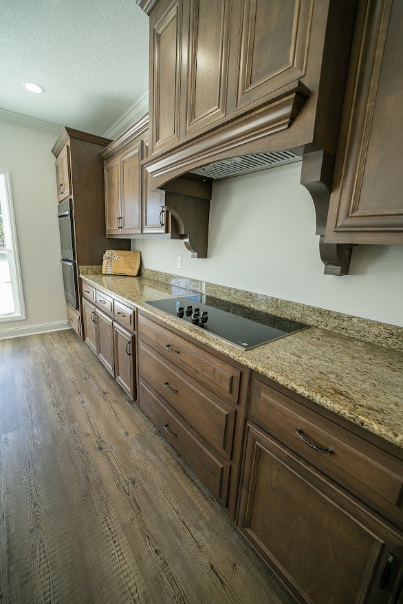 Kitchen featuring natural wood cabinets, stainless steel stove, stone countertop, and tiled backsplash