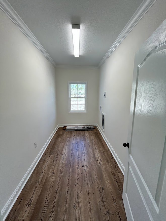 Hallway with wood flooring, white door, white-framed window, ceiling light, and plaster walls with molding
