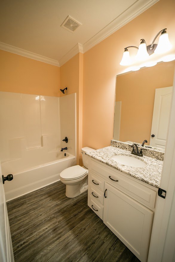 Bathroom with marble countertop sink, white toilet, tiled floor, ceiling vent, and four-bulb light fixture