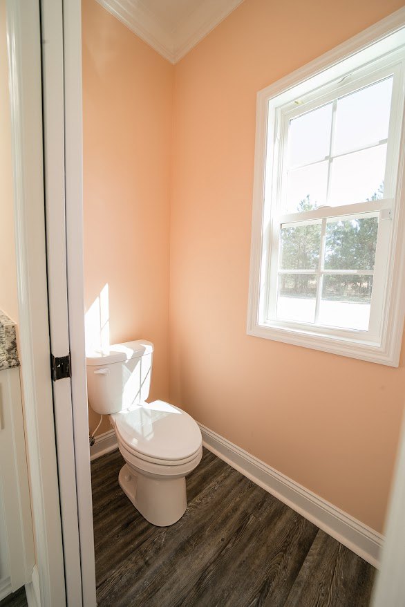 White toilet beside bathtub in bathroom with tiled floor and wall, window above, and chrome plumbing fixtures