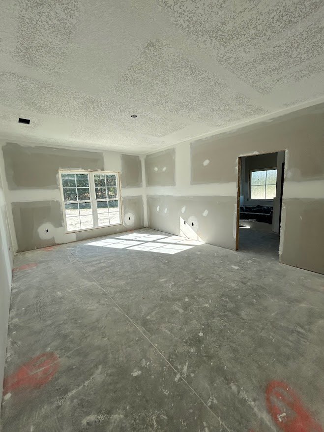 White tile floor reflecting sunlight, plaster walls, frosted glass window, and a wooden door in a bright interior room.