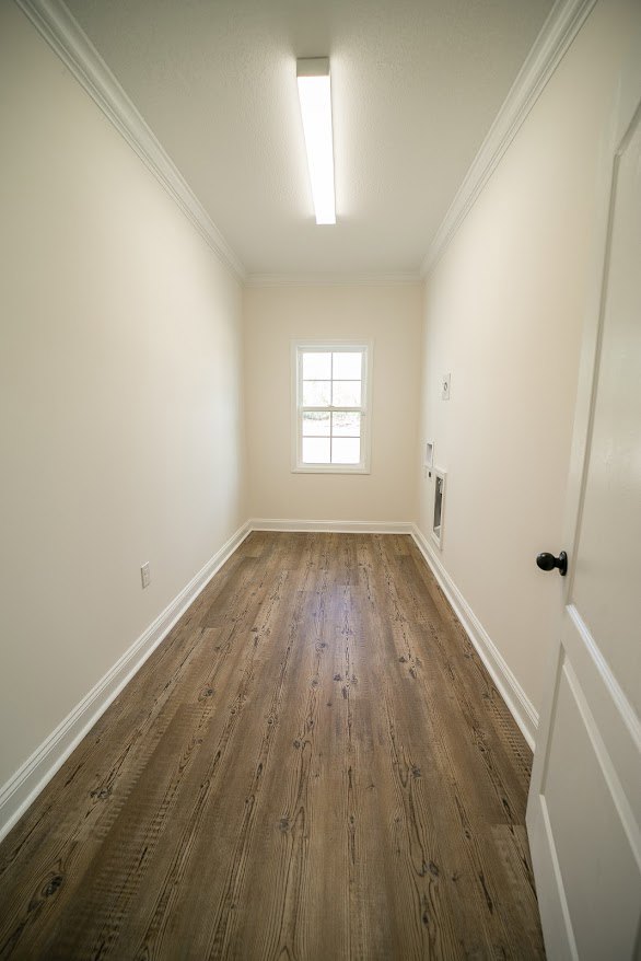 Hallway with light wood flooring, white walls, large window with white frame, white door featuring black handle