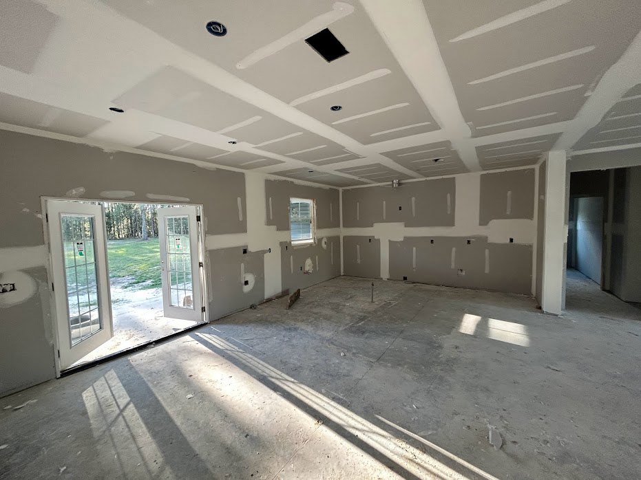 Bright room with white plaster walls, white ceiling, double doors featuring glass panes, sunlight streaming through door, light-colored flooring