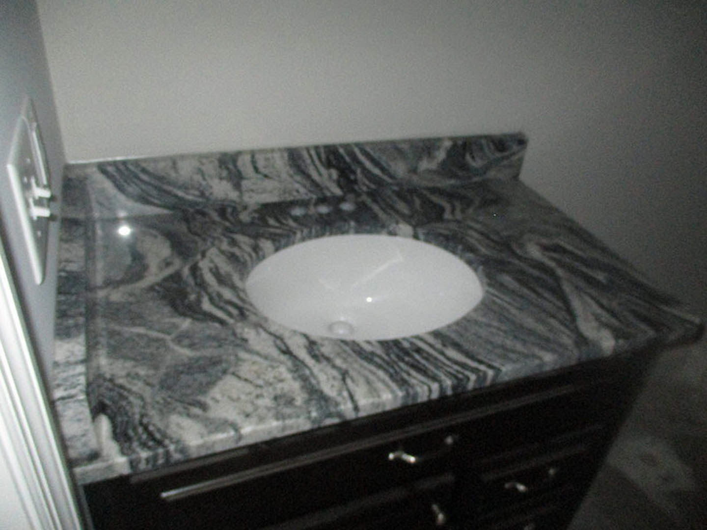 White vessel sink on marble countertop with wood cabinetry and drawers in modern bathroom