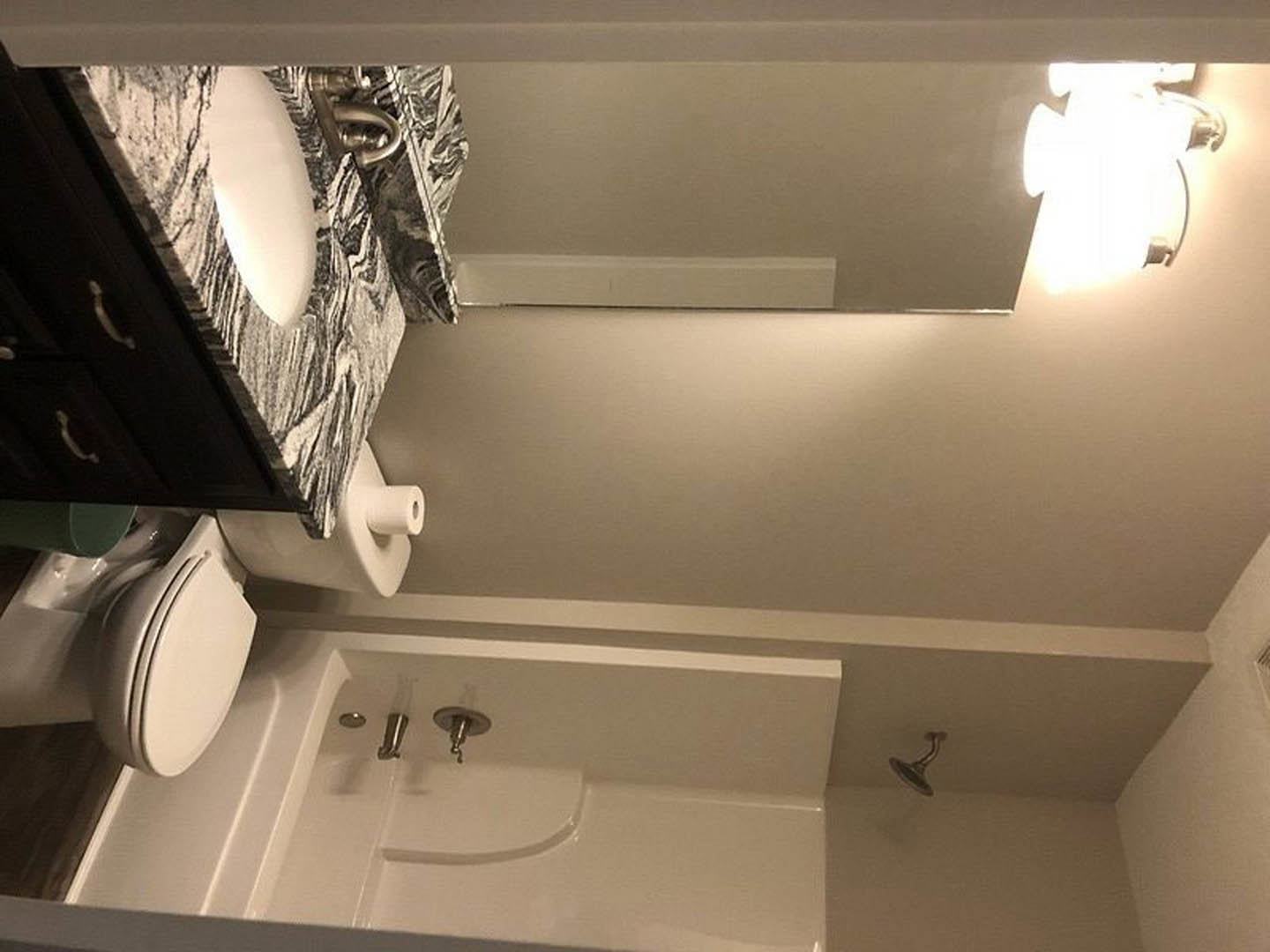 Modern bathroom with white tile walls, glass-enclosed shower, rectangular sink with chrome faucet, wall-mounted light fixture, and freestanding bathtub