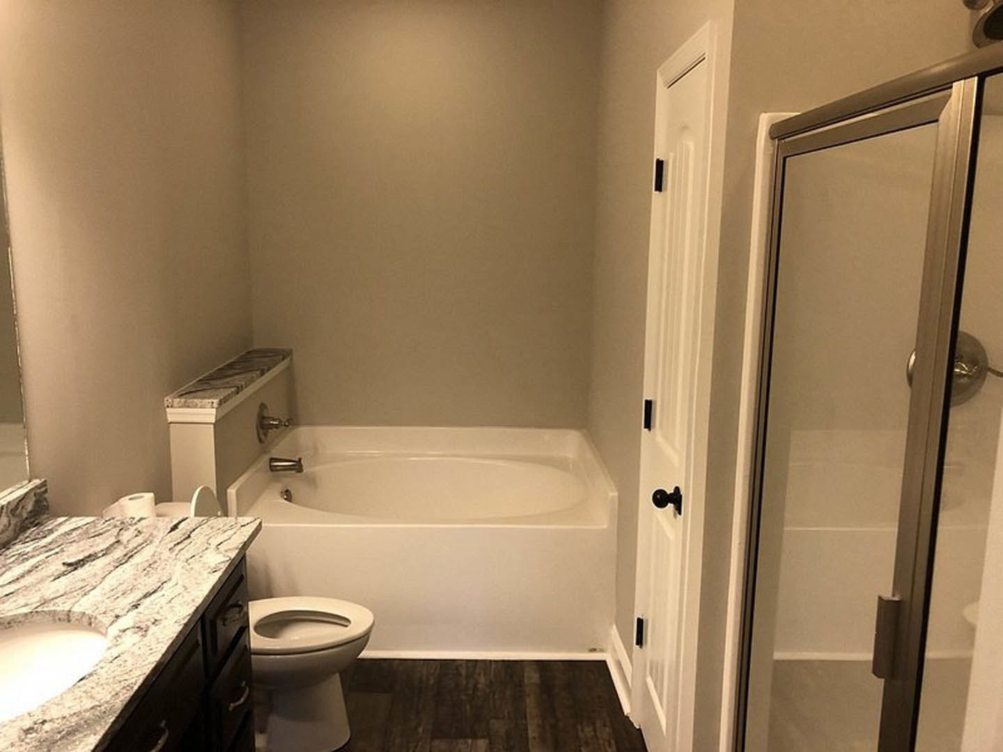 Bathroom with marble countertop, white sink, glass shower door, tiled walls, and toilet with seat down