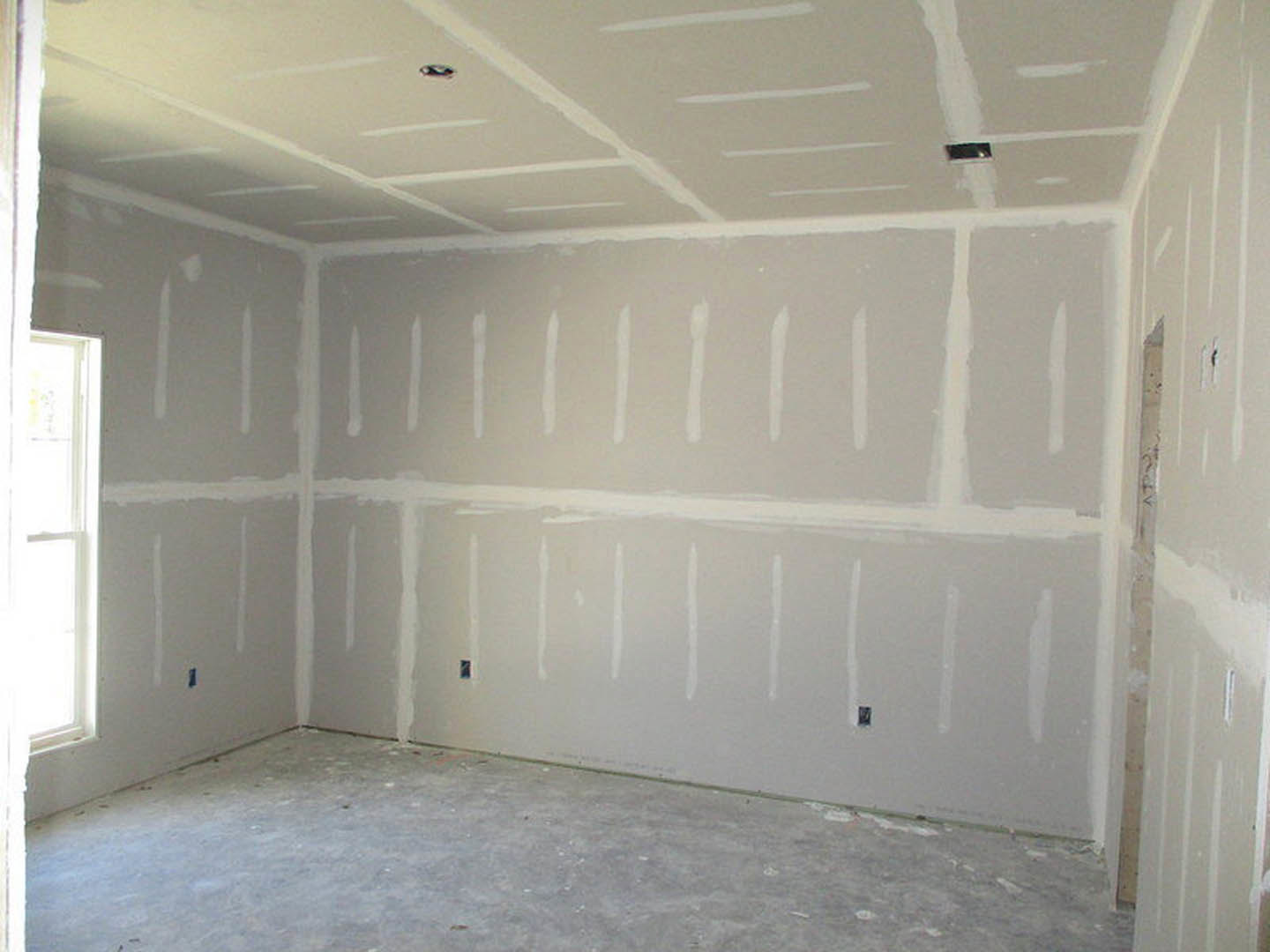 Modern room with smooth white plaster walls, linear white ceiling panels, large window, and polished concrete floor