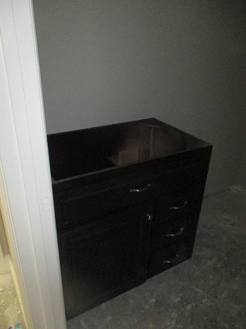 Dark wood cabinet with multiple drawers against a light-colored wall on hardwood flooring