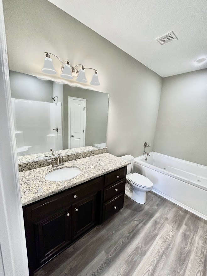 Bathroom with marble countertop, undermount sink, freestanding bathtub, white tile flooring, and modern cabinetry