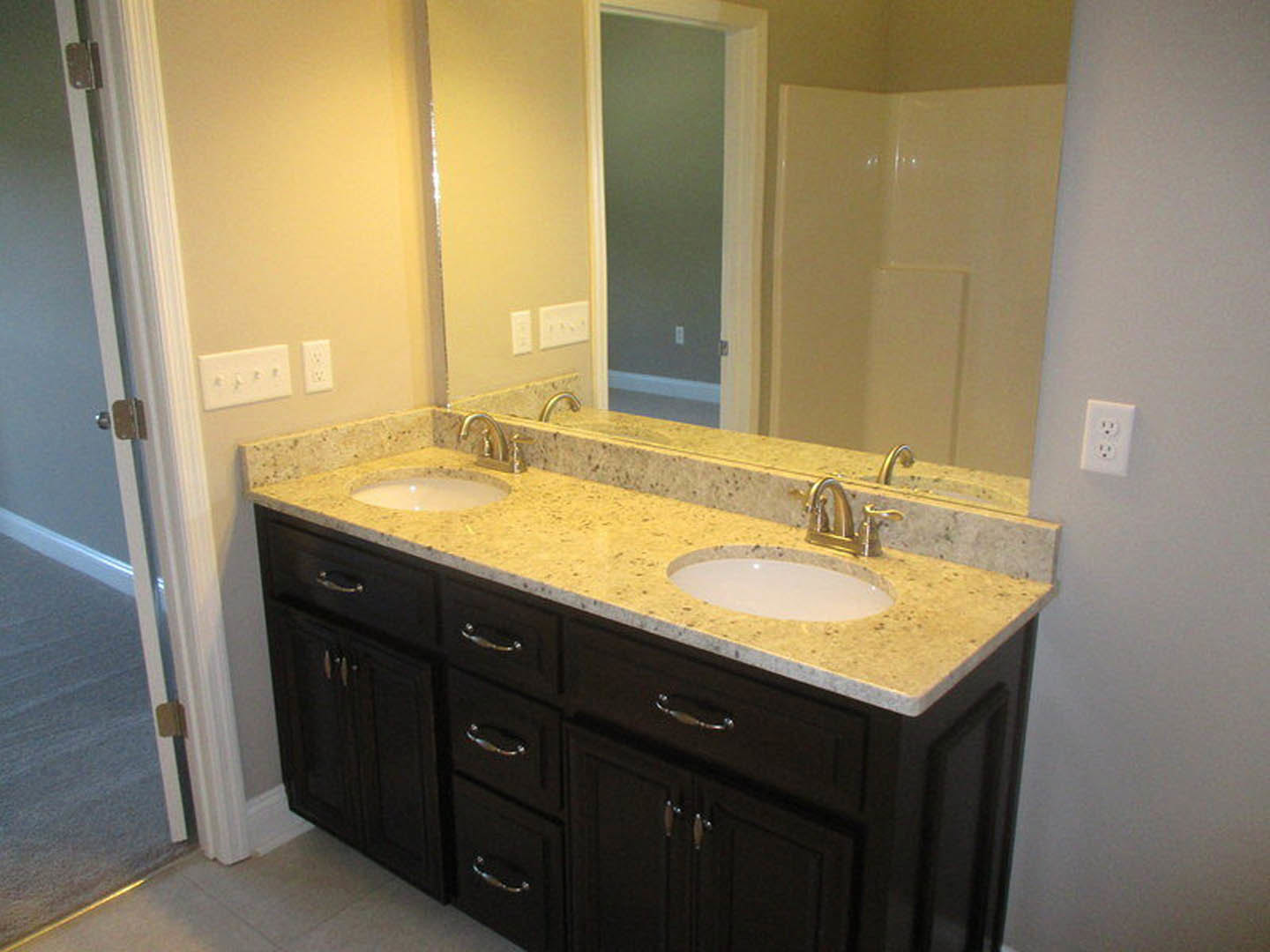 Bathroom with double vanity featuring undermount sinks, wide mirror above, white quartz countertop, chrome faucets, light gray tile backsplash, and shaker-style cabinetry.